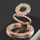Rose gold phone ring stand with glittery design on a reflective surface